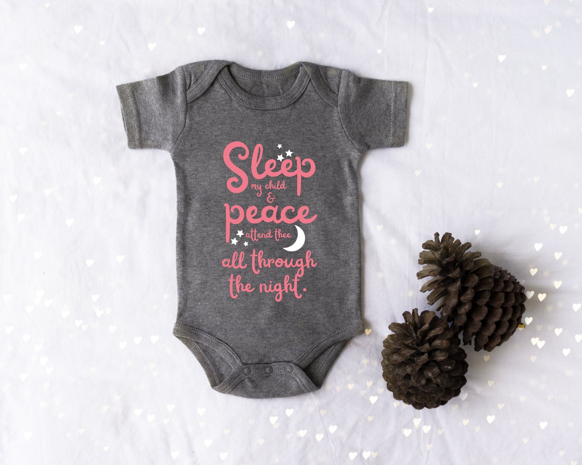 Gray baby onesie with pink lettering with the words from the lullaby, "Sleep my child and peace attend thee all through the night." Stars and moon in white.