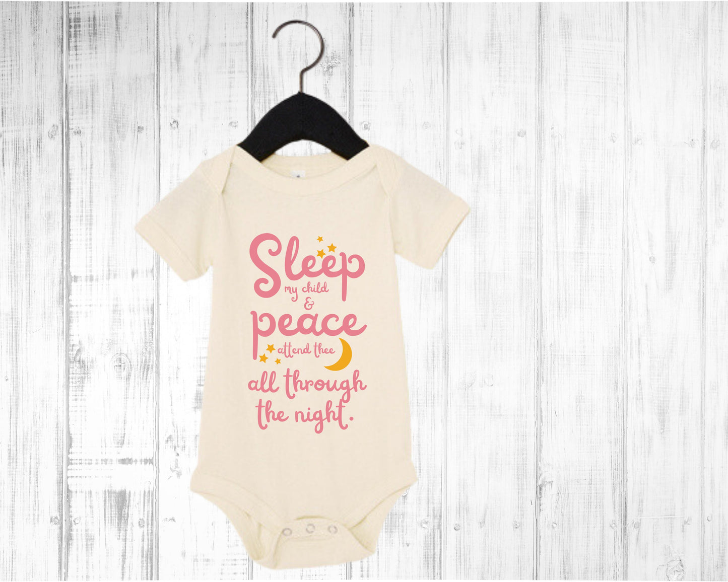 Naturawl baby onesie with pink lettering with the words from the lullaby, "Sleep my child and peace attend thee all through the night." Stars and moon in gold.