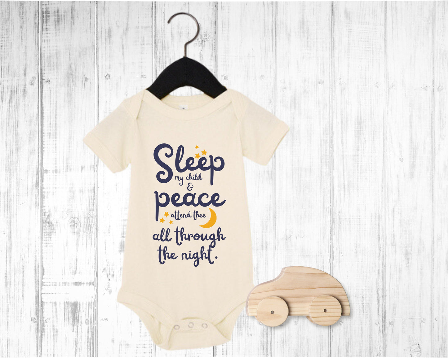 Natural baby onesie with navy lettering with the words from the lullaby, "Sleep my child and peace attend thee all through the night." Stars and moon in gold.