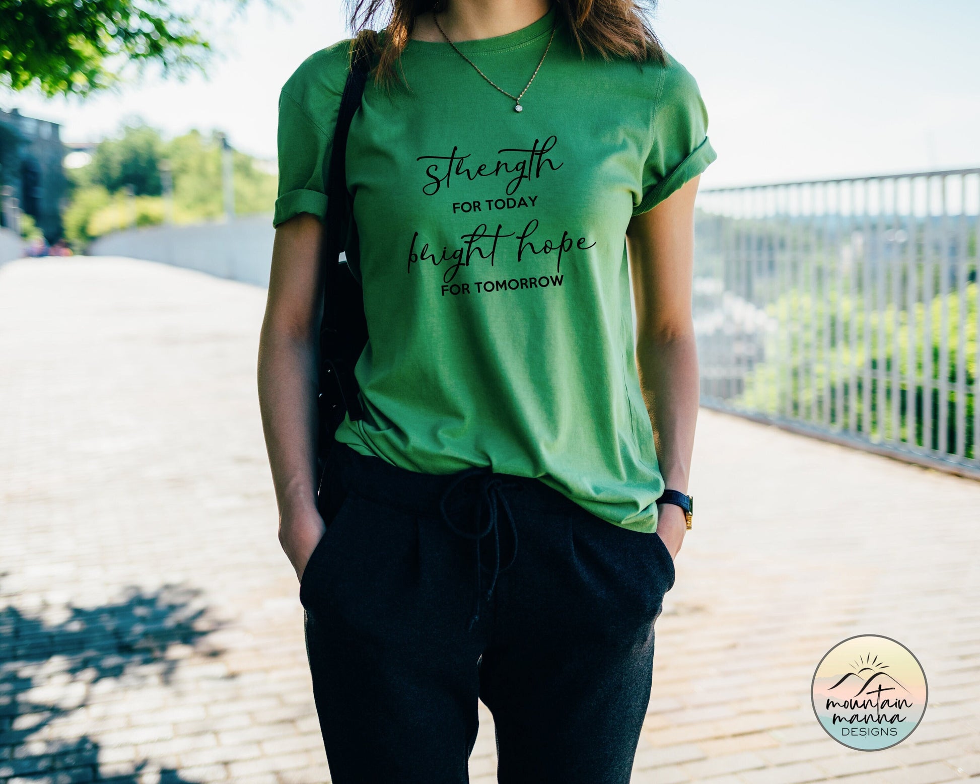 Kelly green tee on a model standing on a boardwalk. The words &quot;Strength for Today and Bright Hope for Tomorrow&quot; on the front of the shirt.